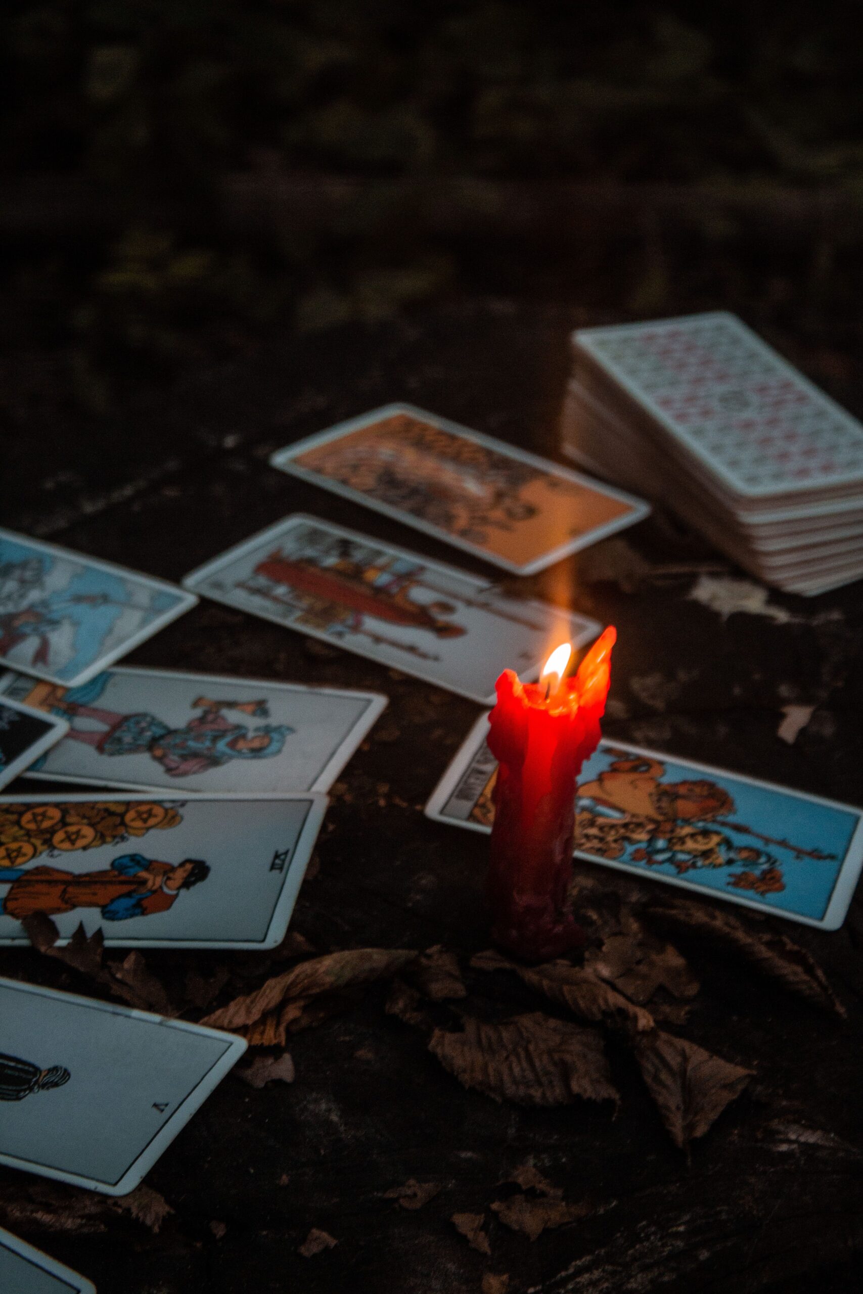 Atmospheric shot of tarot cards with a burning red candle, creating a mystical ambiance.